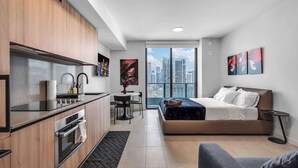 Ein modernes Hotelzimmer mit Küchenzeile, einem Bett, einer Couch und Blick auf die Stadt.