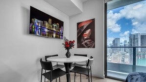 Ein moderner Essbereich mit einem runden Tisch, vier Stühlen, einer Vase mit roten Blumen und zwei Bildern an der Wand.