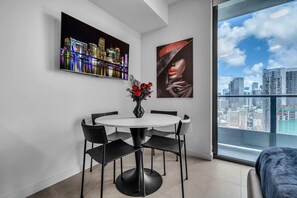 Ein moderner Essbereich mit einem runden Tisch, vier Stühlen, einer Vase mit roten Blumen und zwei Bildern an der Wand.