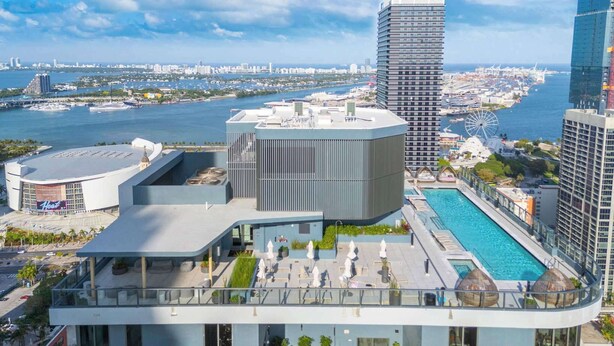 Ein modernes Hotel mit Dachpool, Blick auf die Stadtlandschaft und einem Hafen im Hintergrund.