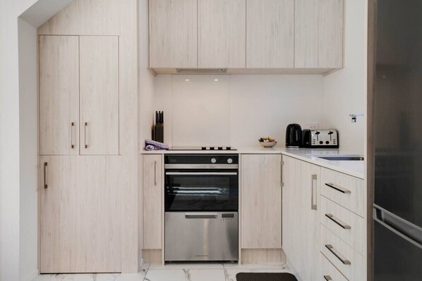 A compact kitchen with a built-in oven, a coffee maker, and a toaster.