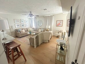 A living room with a sofa, coffee table, and a television mounted on the wall. - Charming waterfront  3bed, 3bath house minutes from Mississippi State University (Starkville)