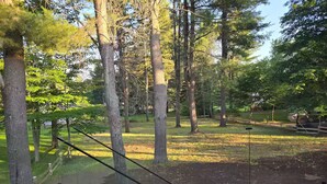 A wooden deck with a glass balustrade overlooking a grassy area with trees. - Luxury Modern Cottage | 4 Ensuite Bedrooms | Sleeps 10 | Near Lake (Sundridge)