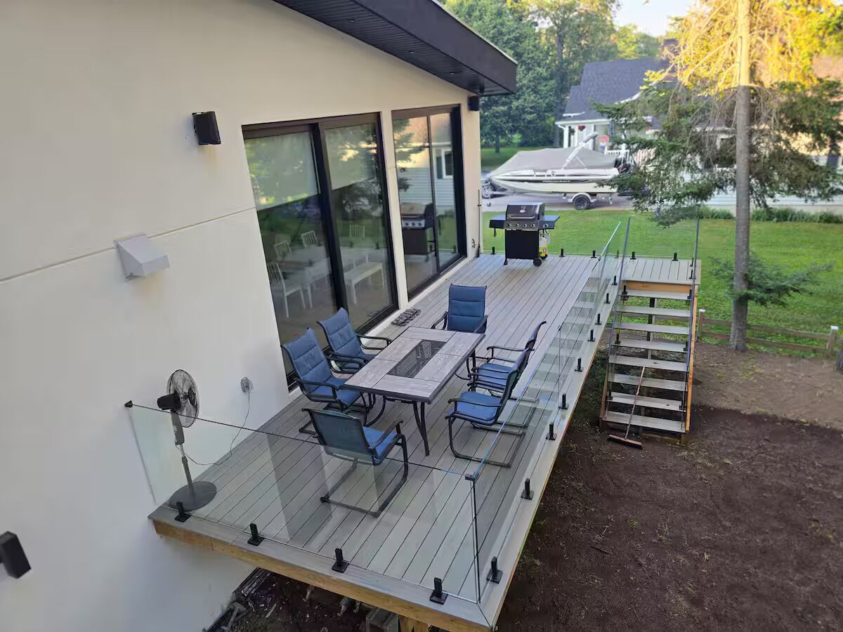 En overdækket terrasse med et bord, stole, ventilator og grill.