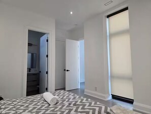 Une chambre à coucher comprenant un lit, un dressing et une porte coulissante donnant sur une autre pièce.