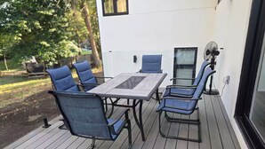 An outdoor deck with a table and chairs, a fan, and a view of a house. - Luxury Modern Cottage | 4 Ensuite Bedrooms | Sleeps 10 | Near Lake (Sundridge)