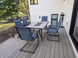 An outdoor deck with a table and chairs, a fan, and a view of a house. - Luxury Modern Cottage | 4 Ensuite Bedrooms | Sleeps 10 | Near Lake (Sundridge)