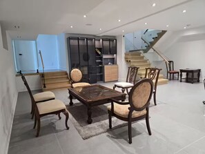 Ein großzügiger Wohnbereich mit einem Glastisch, Holzstühlen, einer Couch und einer Treppe, die zu einer oberen Etage führt.