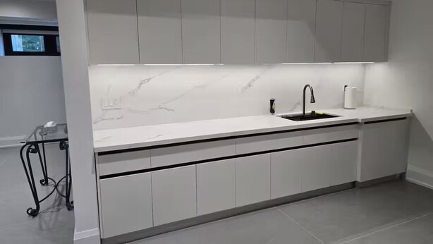 A modern kitchen with white cabinetry, a marble countertop, and a black faucet. - Luxury Modern Cottage | 4 Ensuite Bedrooms | Sleeps 10 | Near Lake (Sundridge)