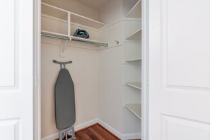 A walk-in closet with shelves, a hanging rod, and an ironing board. - Blueground | Ballston, pool, nr Arlington Cemetery (Arlington)