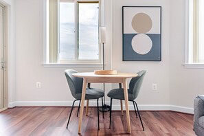 A dining area with a round table, two chairs, a floor lamp, and a wall-mounted abstract painting. - Blueground | Ballston, pool, nr Arlington Cemetery (Arlington)
