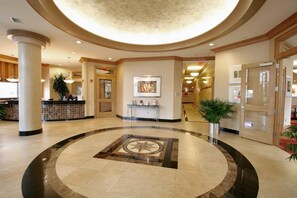 Et hotel lobby med et centralt cirkulært design, en receptionsdisk og et indrammet kunstværk på væggen.