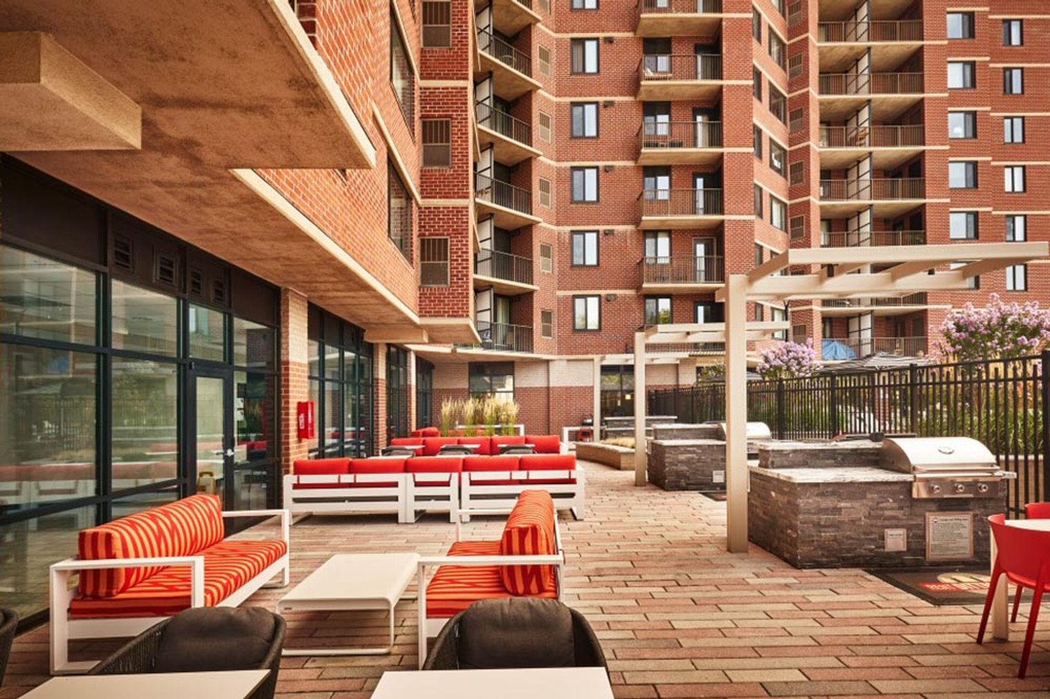 A rooftop patio with outdoor seating, a barbecue grill, and a view of a high-rise building.