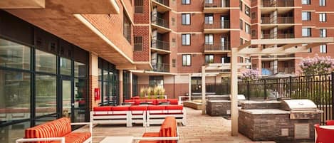 En tagterrasse med udendørs møbler, grill og udsigt til en skyskraber.