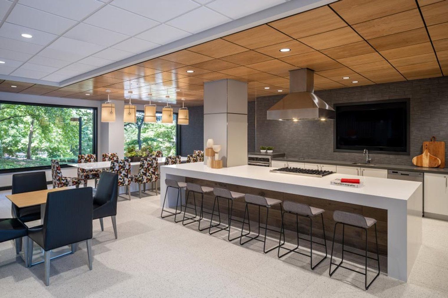 Une cuisine moderne dotée d’un grand îlot central, de tabourets de bar et de luminaires suspendus.
