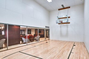 A spacious indoor area with a basketball court, a seating area with red chairs, and a glass partition. - Blueground | Clarendon, pool, nr Arlington Cemetery (Arlington)