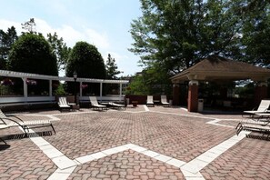 A covered outdoor area with brick flooring, lounge chairs, and a gazebo. - Blueground | Clarendon, pool, nr Arlington Cemetery (Arlington)