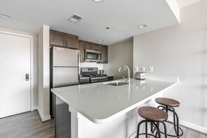 A modern kitchen with a central island, stainless steel appliances, and bar stools. - Blueground | Clarendon, pool, nr Arlington Cemetery (Arlington)