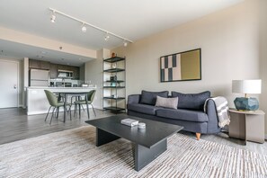 A modern living room with a dark coffee table, a grey sofa, and a striped rug. - Blueground | Clarendon, pool, nr Arlington Cemetery (Arlington)