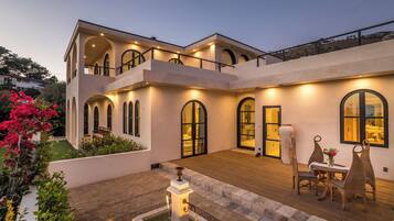 Uma casa moderna de dois andares com um pátio, uma fonte e área de estar externa.