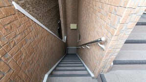 A stairway with a handrail, brick walls, and a tiled floor. - Suncity Hakata (Fukuoka City Hakataku  Katakasu)