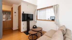 A compact living space with a kitchenette, a flat-screen TV, a small round table, and a sofa. - Suncity Hakata (Fukuoka City Hakataku  Katakasu)