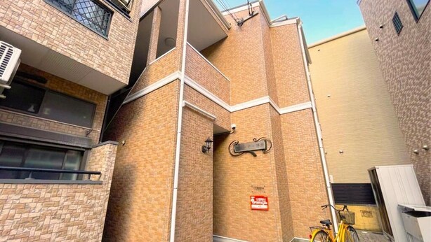 A multi-story building with a brick facade, a bicycle parked outside, and a fire safety sign. - Suncity Hakata (Fukuoka City Hakataku  Katakasu)