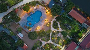 Vista aerea di una proprietà con piscina centrale, circondata da giardini curati e vialetti.