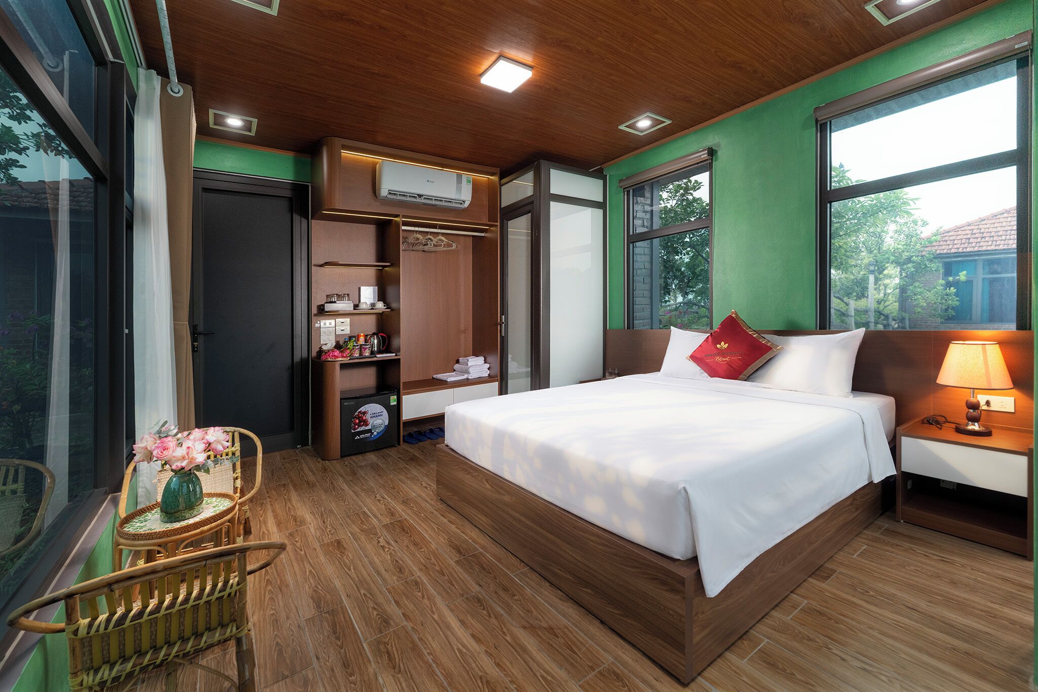 Ein Hotelzimmer mit Bett, Nachttisch, Lampe, Kleiderschrank und einem Fenster mit Blick.