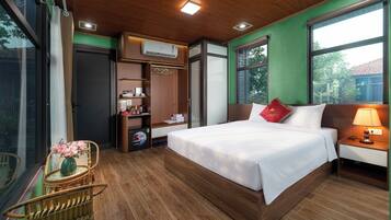 Ein Hotelzimmer mit Bett, Nachttisch, Lampe, Kleiderschrank und einem Fenster mit Blick.