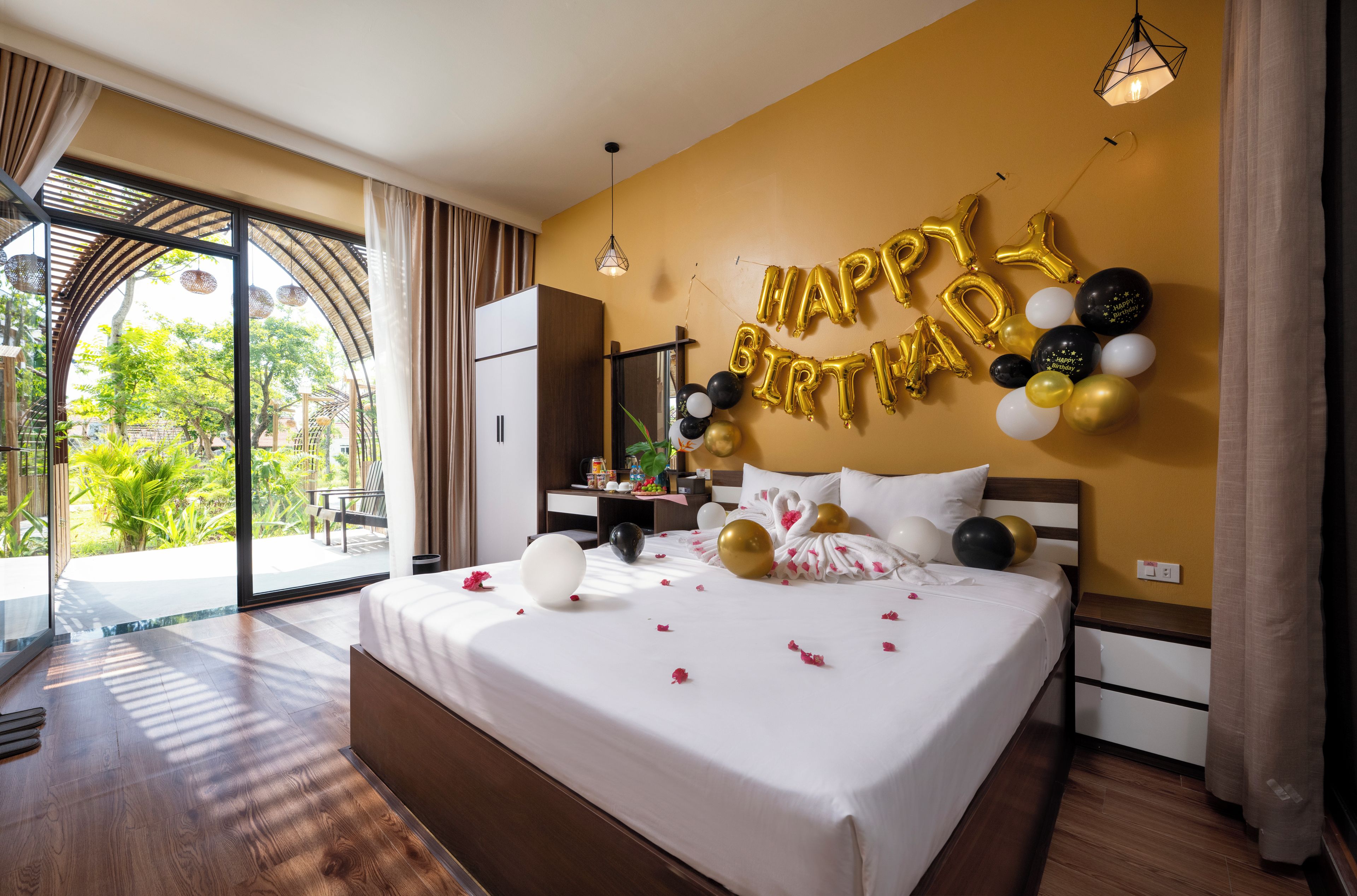 Habitación de hotel con una cama, vistas al exterior y una decoración de 'Happy Birthday'.
