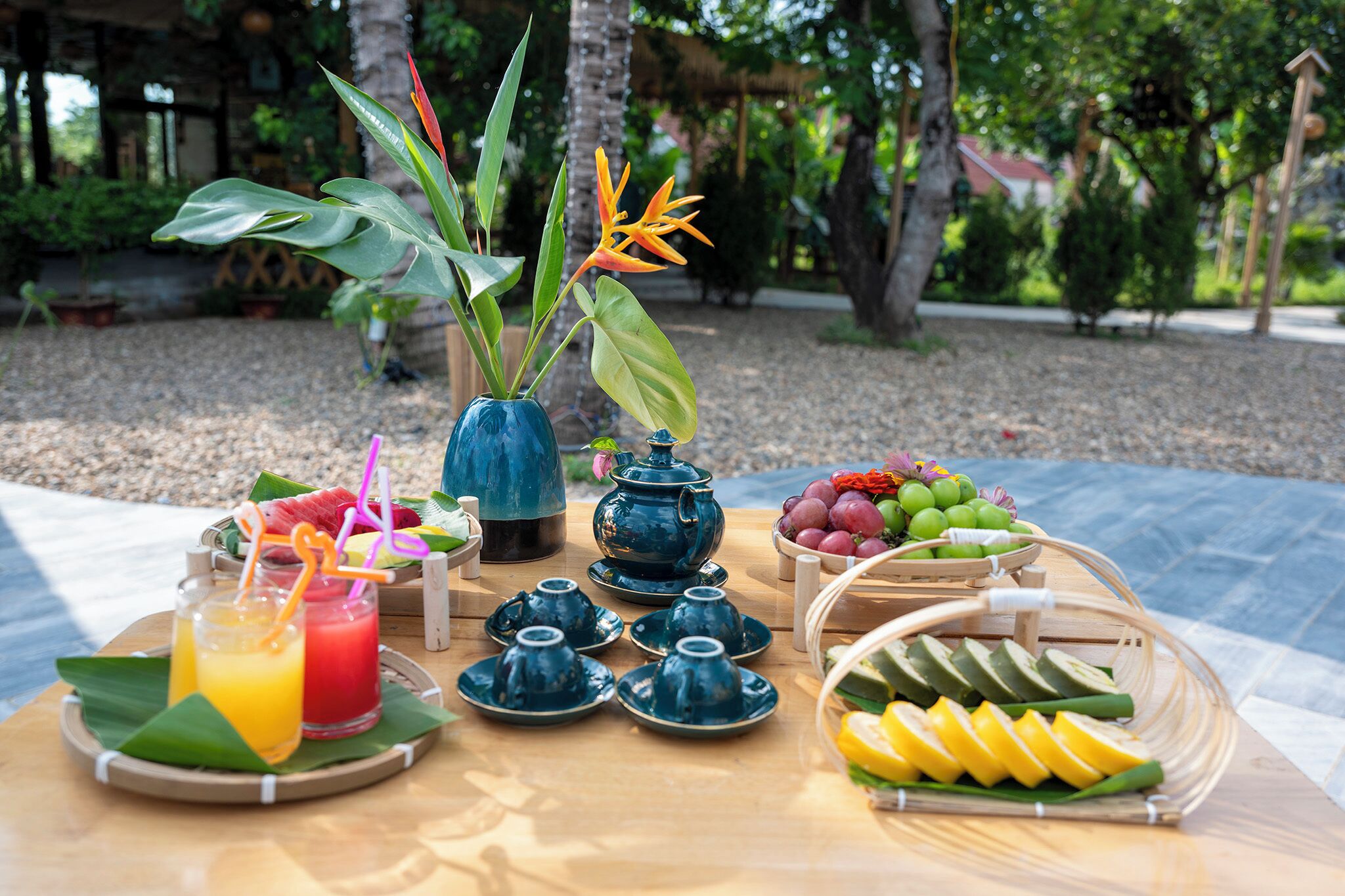 Una mesa dispuesta con diversos alimentos, entre ellos frutas, una tetera y un florero con flores.