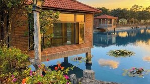 Una struttura in legno con porte di vetro, un edificio in mattoni e una distesa d'acqua con ninfee.