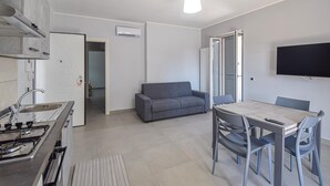 Een moderne keuken met een gasfornuis, een spoelbak en een eethoek met een tafel en stoelen.