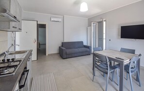 A modern kitchen with a gas stove, a sink, and a dining area with a table and chairs. - 2 bedroom gorgeous apartment in Casoria (Casoria)