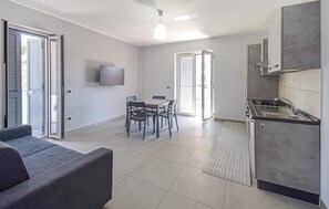A modern living space with a dining area, kitchen, and a flat-screen TV mounted on the wall. - Beautiful apartment in Casoria with WiFi (Casoria)