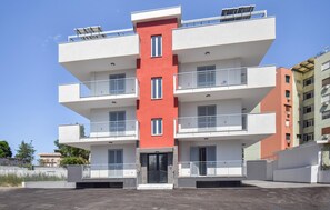 A multi-story residential building with balconies, a central entrance, and a parking area in front. - Beautiful apartment in Casoria with WiFi (Casoria)