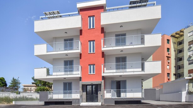 A multi-story residential building with balconies, a central entrance, and solar panels on the roof. - Amazing apartment in Casoria with WiFi (Casoria)
