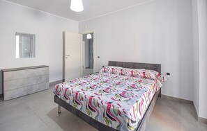 Ein Schlafzimmer mit Bett, Kommode, Spiegel und Tür.