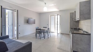 A modern kitchen with a built-in stove and a dining area with a table and chairs. - Amazing apartment in Casoria with WiFi (Casoria)