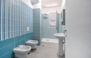 Ein Badezimmer mit blauen Fliesen, einer Dusche, einer Toilette und einem Bidet.