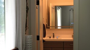 Ein Hotelzimmer mit Bett, einem Badezimmer mit Waschbecken und Spiegel sowie Blick ins Freie.