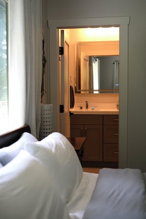 Ein Hotelzimmer mit Bett, einem Badezimmer mit Waschbecken und Spiegel sowie Blick ins Freie.