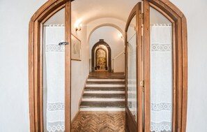 A hallway with wooden doors, a staircase, and a mural on the wall.