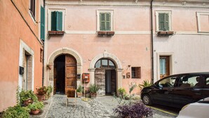 A building with a cobblestone entrance, wooden doors, and green shutters.