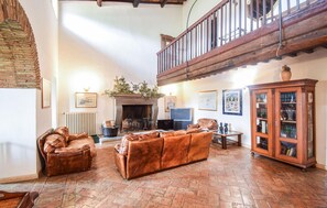 A spacious living room with leather sofas, a fireplace, a television, and a wooden cabinet.