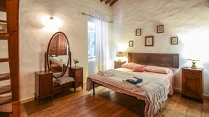 A bedroom with a wooden bed, a nightstand, a dresser, a mirror, and a window with curtains.