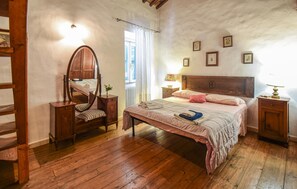 A bedroom with a wooden bed, a nightstand, a dresser, a mirror, and a window with curtains.