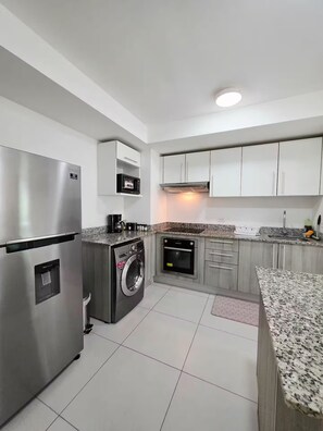 A modern kitchen with stainless steel appliances, a built-in washer, and granite countertops. - Blissful Breeze Retreat with Pool & Workspace (Barreal)