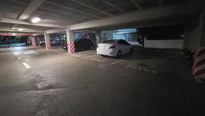 Eine Tiefgarage mit Betonpfeilern, gekennzeichneten Parkplätzen und einem am Rand abgestellten Motorrad.